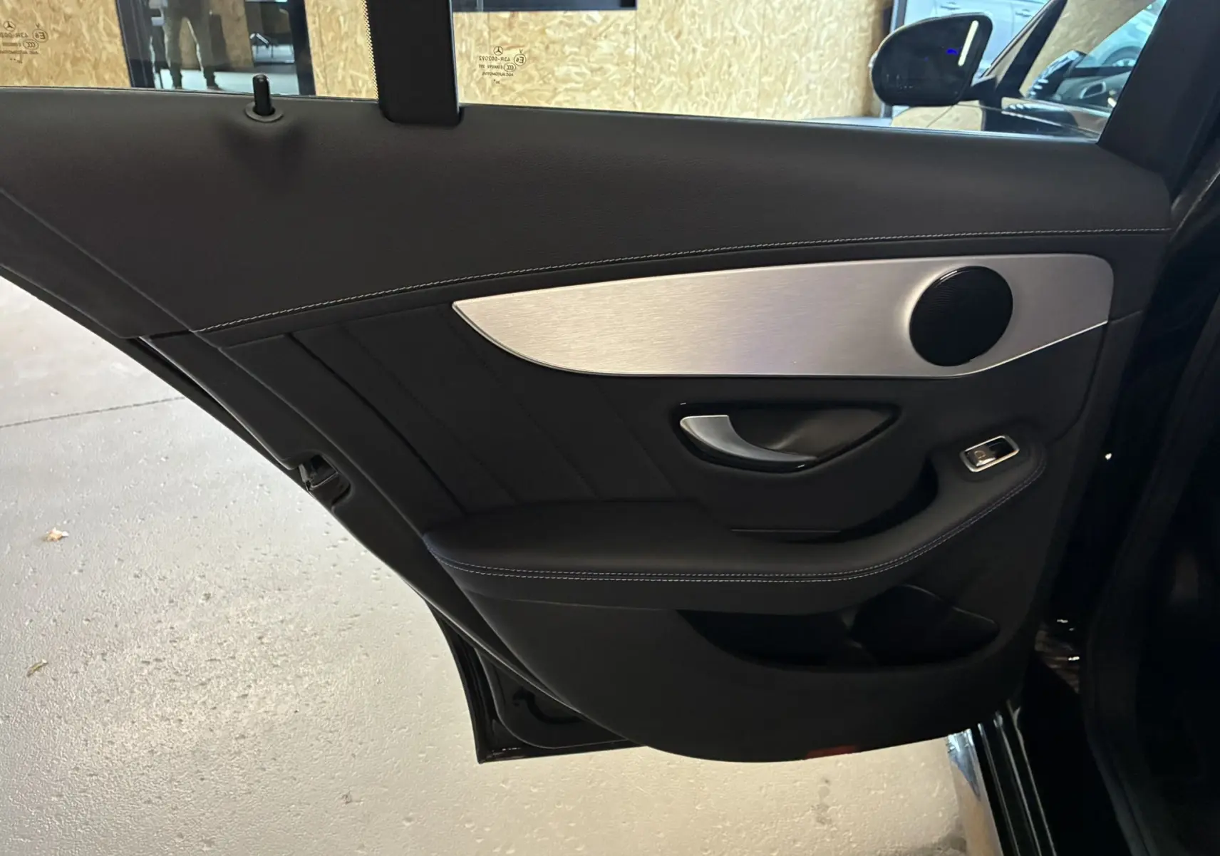 Gros plan sur la porte arrière gauche noire du Mercedes Classe C Break 220D AMG Line avec insert aluminium et haut-parleur rond.