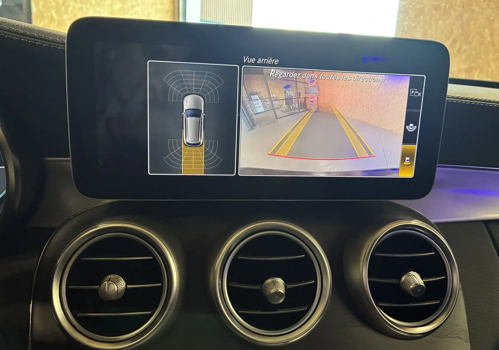 Écran tactile intérieur du Mercedes Classe C Break noir, affichant la caméra de recul et les capteurs de stationnement.