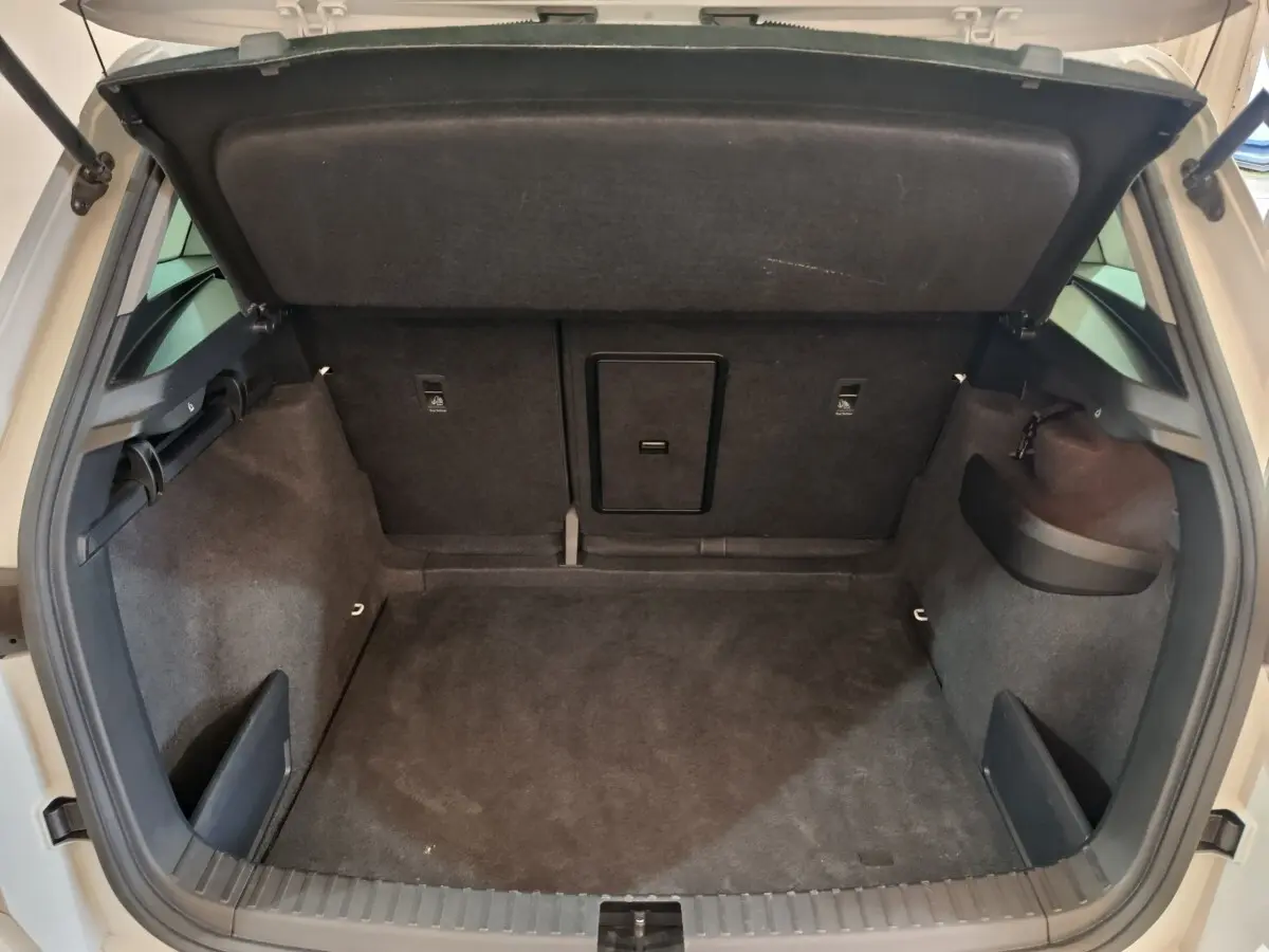 Coffre ouvert du Skoda Karoq blanc 2024, vue intérieure montrant l’espace de chargement et la trappe à ski centrale.
