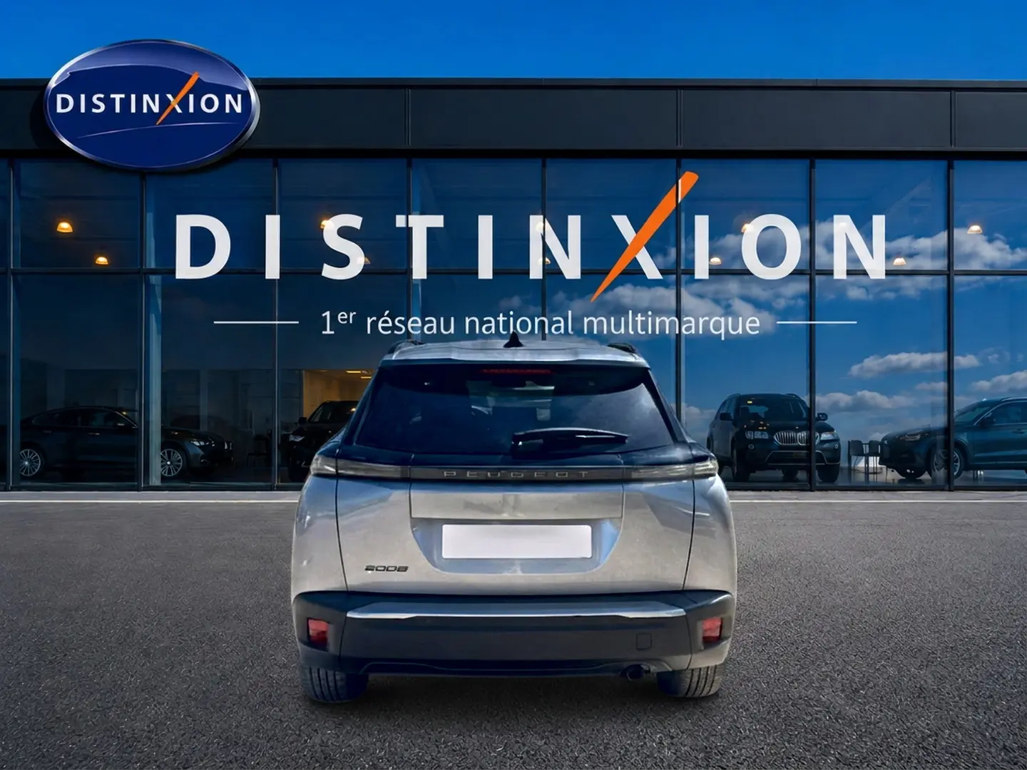 Vue arrière d’un Peugeot 2008 gris artense 2025 garé devant une vitrine avec logo Distinxion.