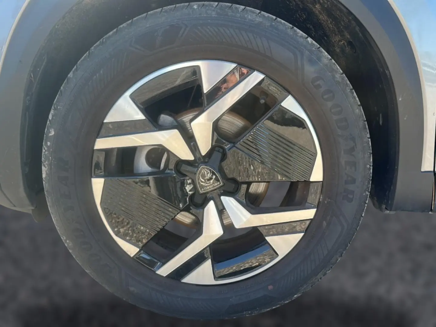 Gros plan sur la jante alu bicolore noire et argentée du Peugeot 2008 gris artense, avec pneu Goodyear visible.