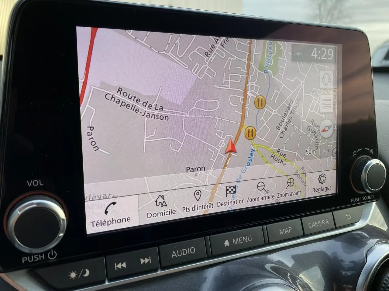 Écran tactile du système GPS du Nissan Juke blanc perle montrant une carte routière en gros plan intérieur.