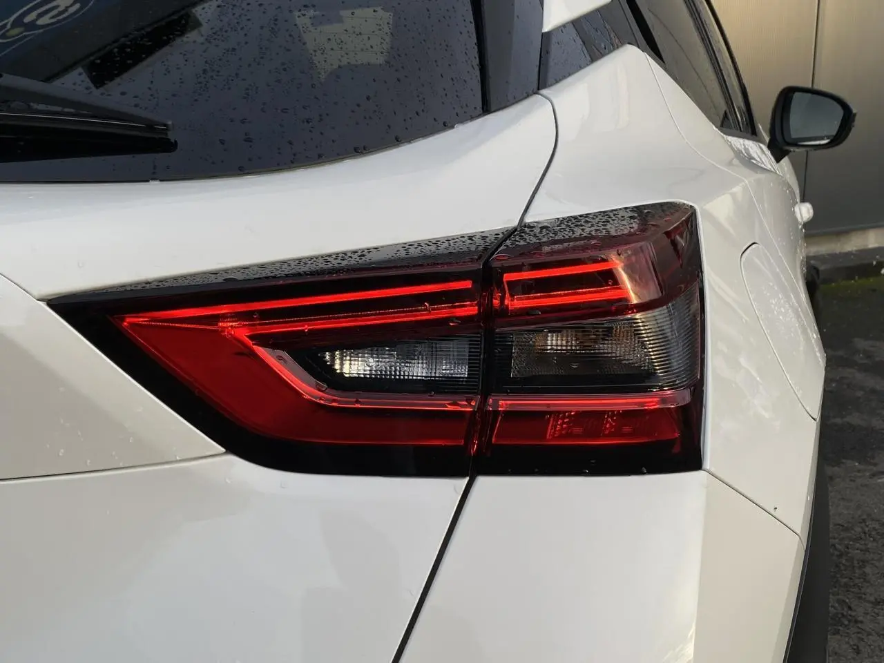 Gros plan sur le feu arrière droit d'un Nissan Juke blanc perle 2024, soulignant ses lignes modernes et épurées.