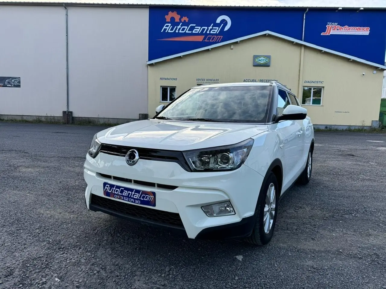 SUV SsangYong Tivoli blanc en 3/4 avant droit, avec calandre noire et phares anguleux visibles sur parking.