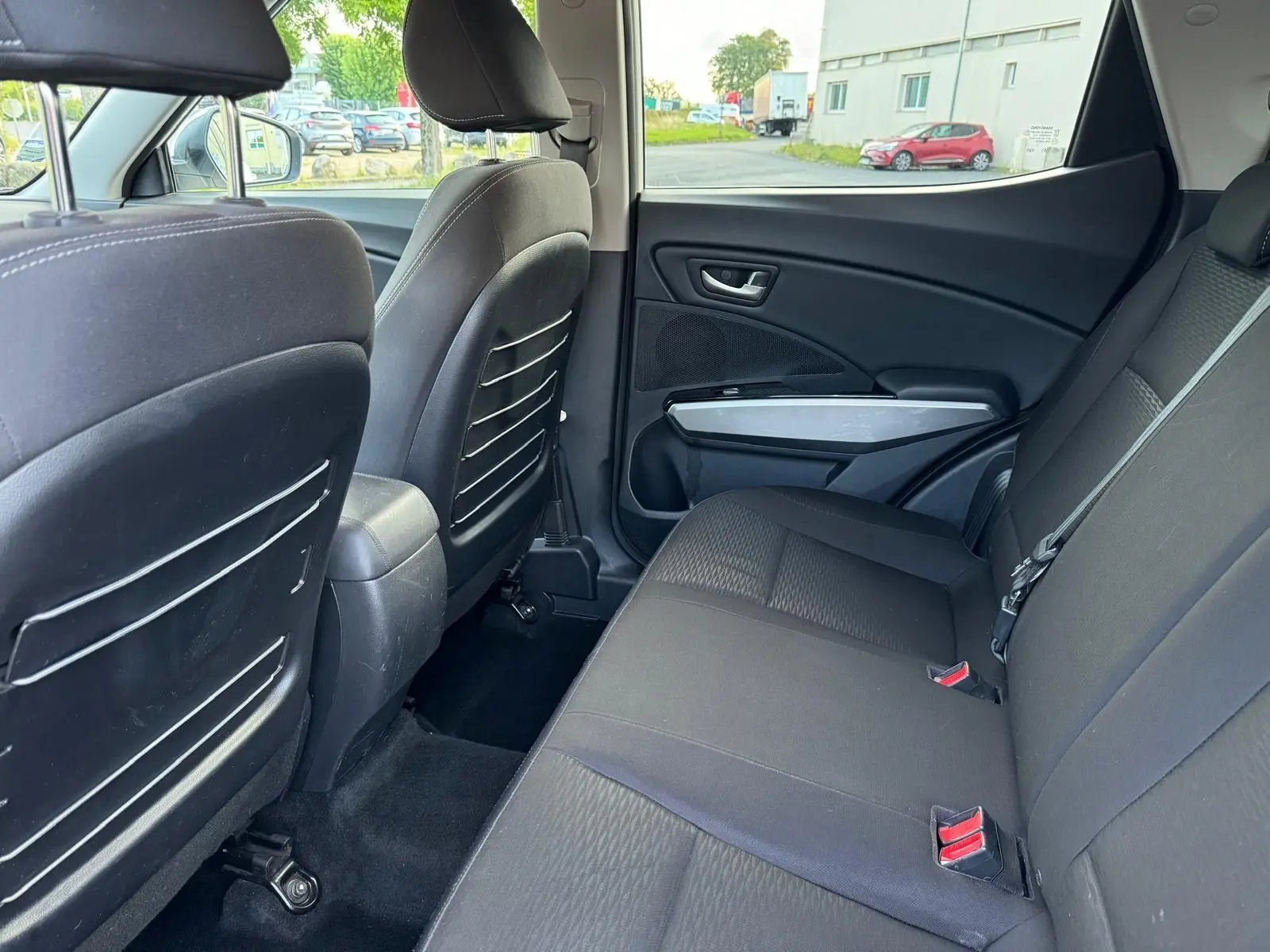 Vue intérieure côté droit des sièges arrière noirs du SsangYong Tivoli blanc 2016, avec appuie-têtes et ceintures visibles.