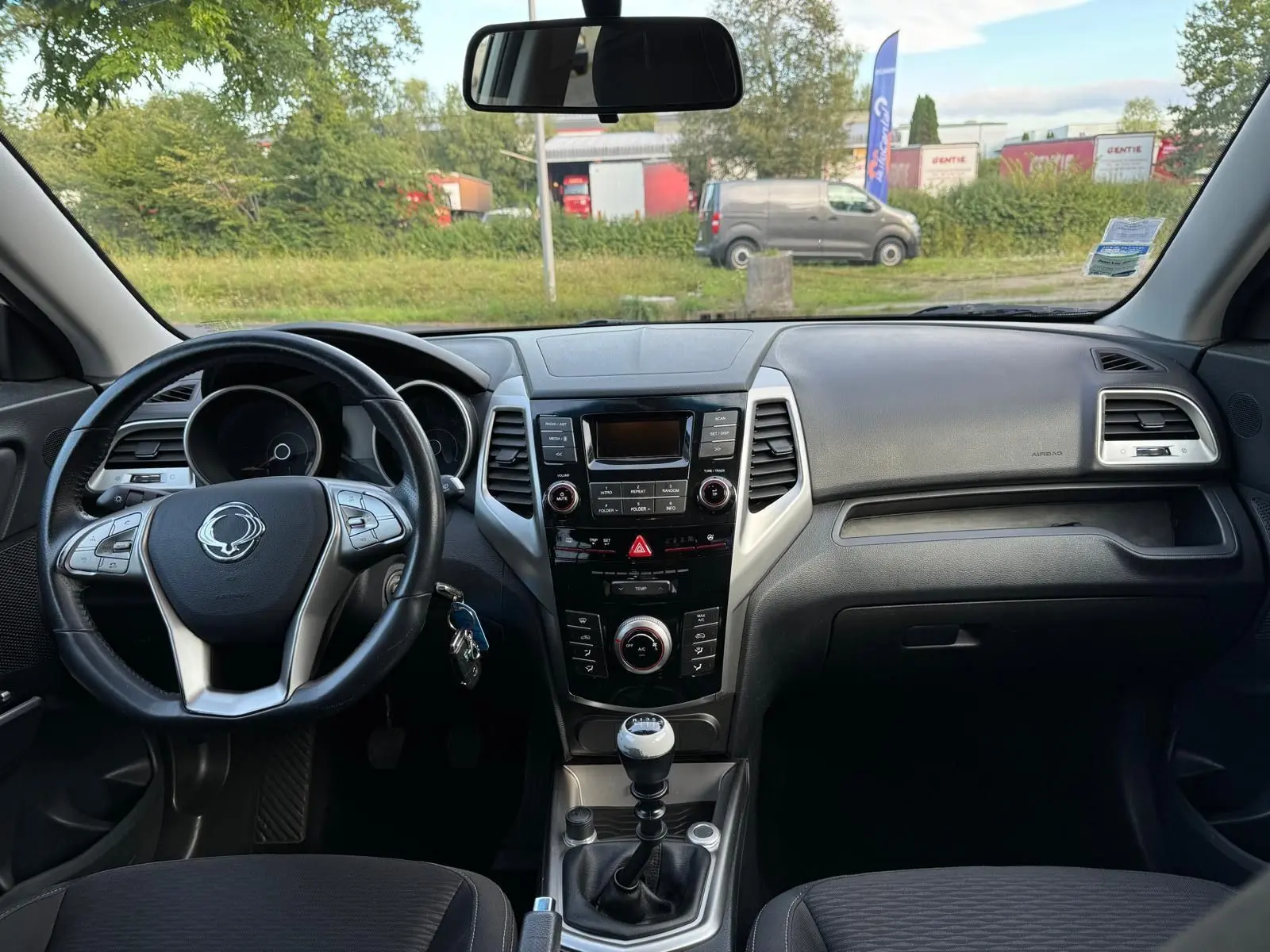 Intérieur du SsangYong Tivoli blanc 2016, vue frontale du tableau de bord avec volant et levier de vitesse manuel.