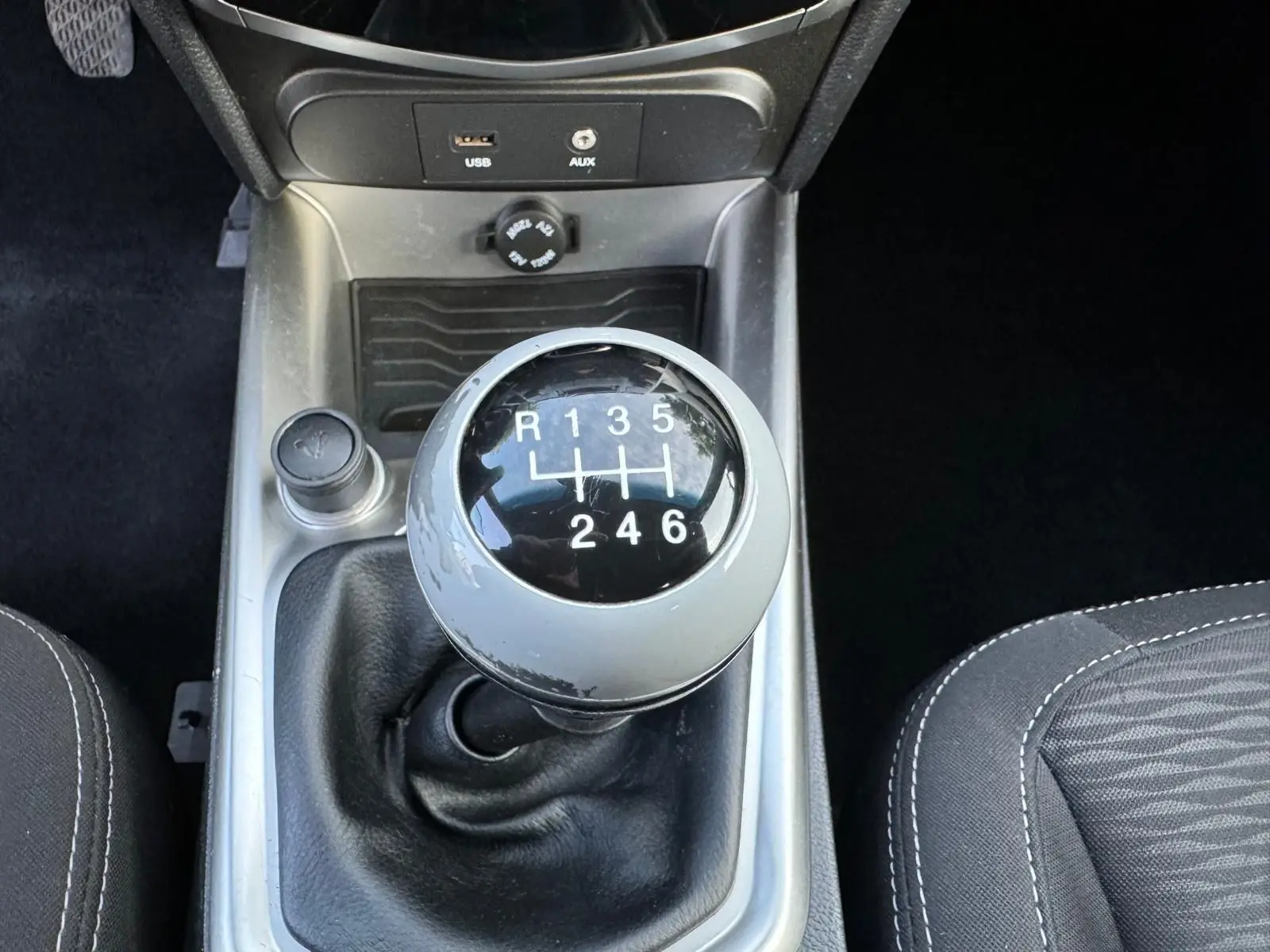 Gros plan sur le levier de vitesses manuel du SsangYong Tivoli blanc 2016 avec prises USB et AUX visibles.