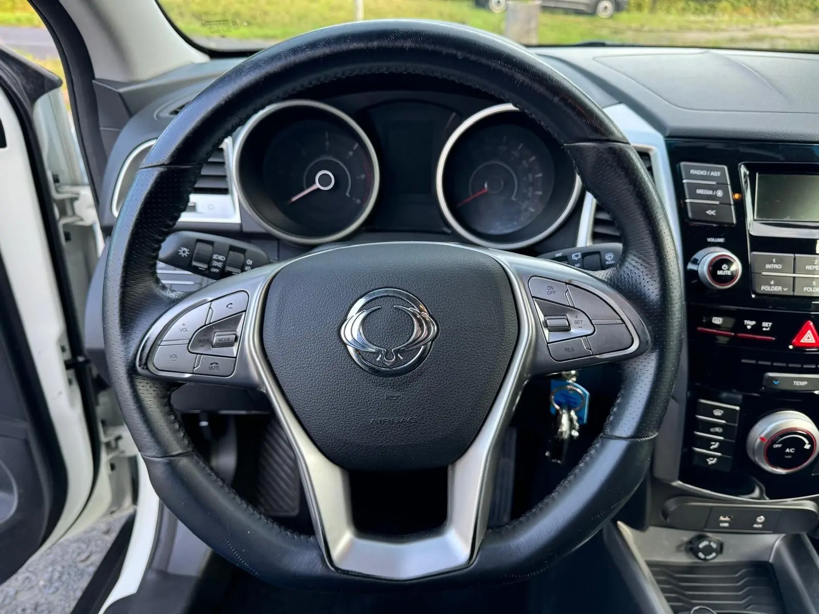 Vue rapprochée du volant en cuir noir du SsangYong Tivoli blanc 2016, avec commandes intégrées et tableau de bord visible.