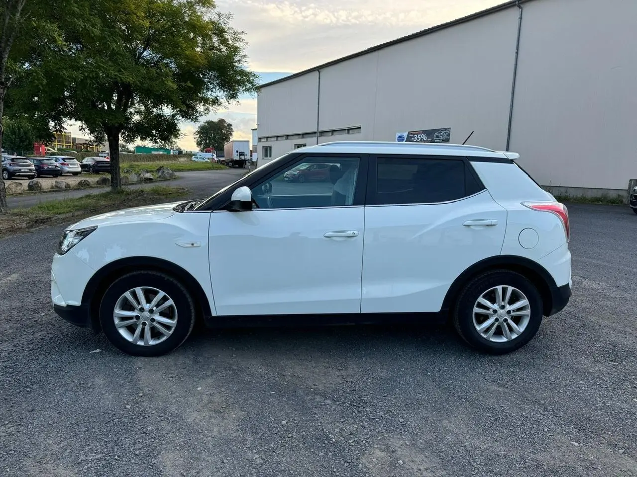 Vue de profil côté gauche d'un SsangYong Tivoli blanc 2016, SUV compact à cinq portes sur un parking extérieur.
