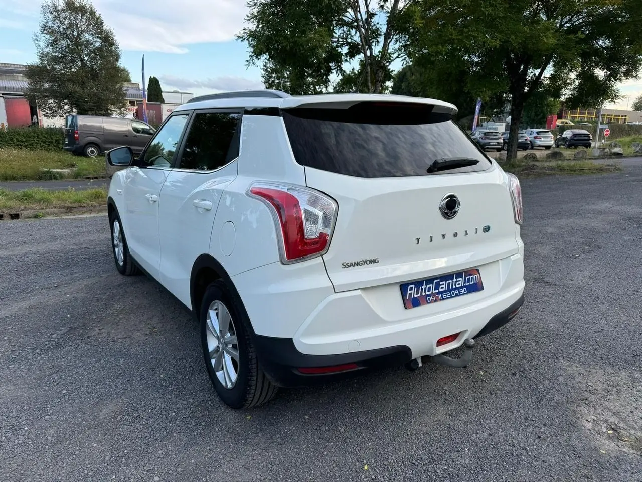 Vue 3/4 arrière droite d'un SsangYong Tivoli blanc 2016 avec hayon teinté et attelage visible sur parking.