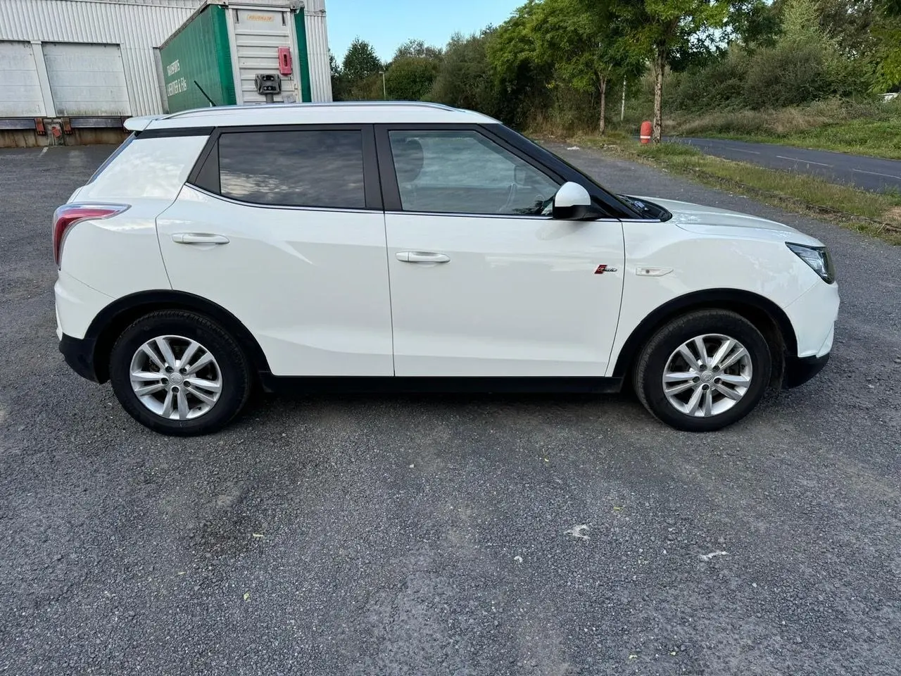 Vue latérale côté gauche d'un SsangYong Tivoli blanc 2016 avec vitres teintées et jantes alliage.