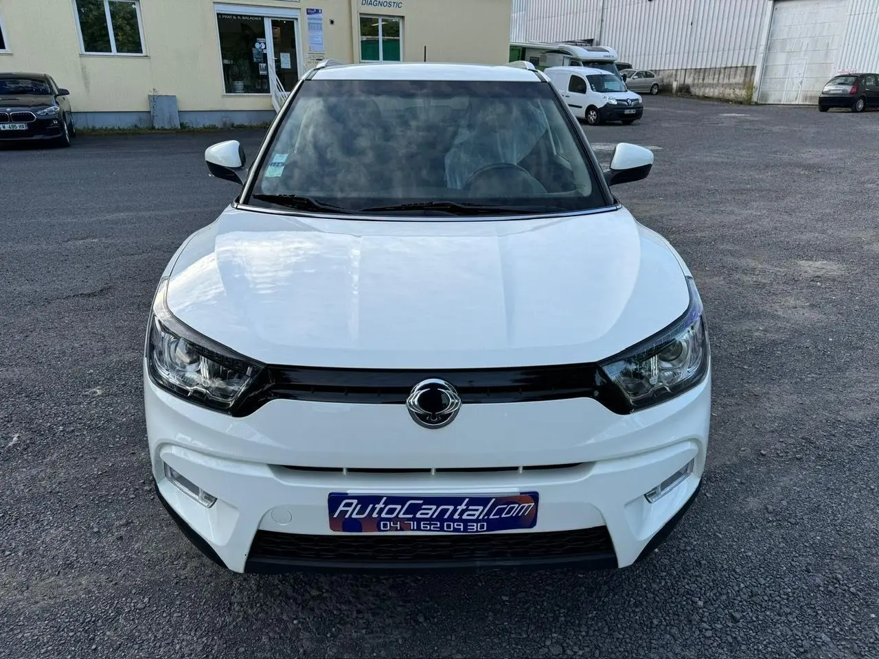 Vue frontale d'un SsangYong Tivoli blanc 2016 avec calandre noire et logo centré sur parking.