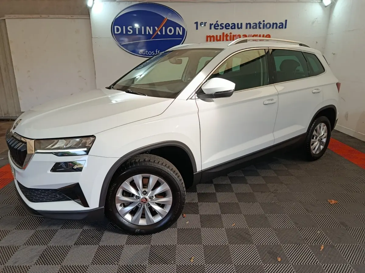 Vue 3/4 avant droit d'un SUV SKODA KAROQ blanc 2024 avec jantes alliage et rétroviseurs blancs.