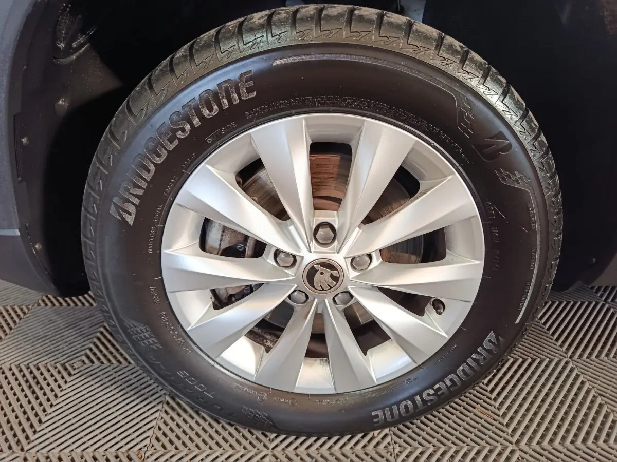 Gros plan sur la jante argentée avec logo SKODA au centre, montée d’un pneu Bridgestone sur un SKODA KAROQ blanc.