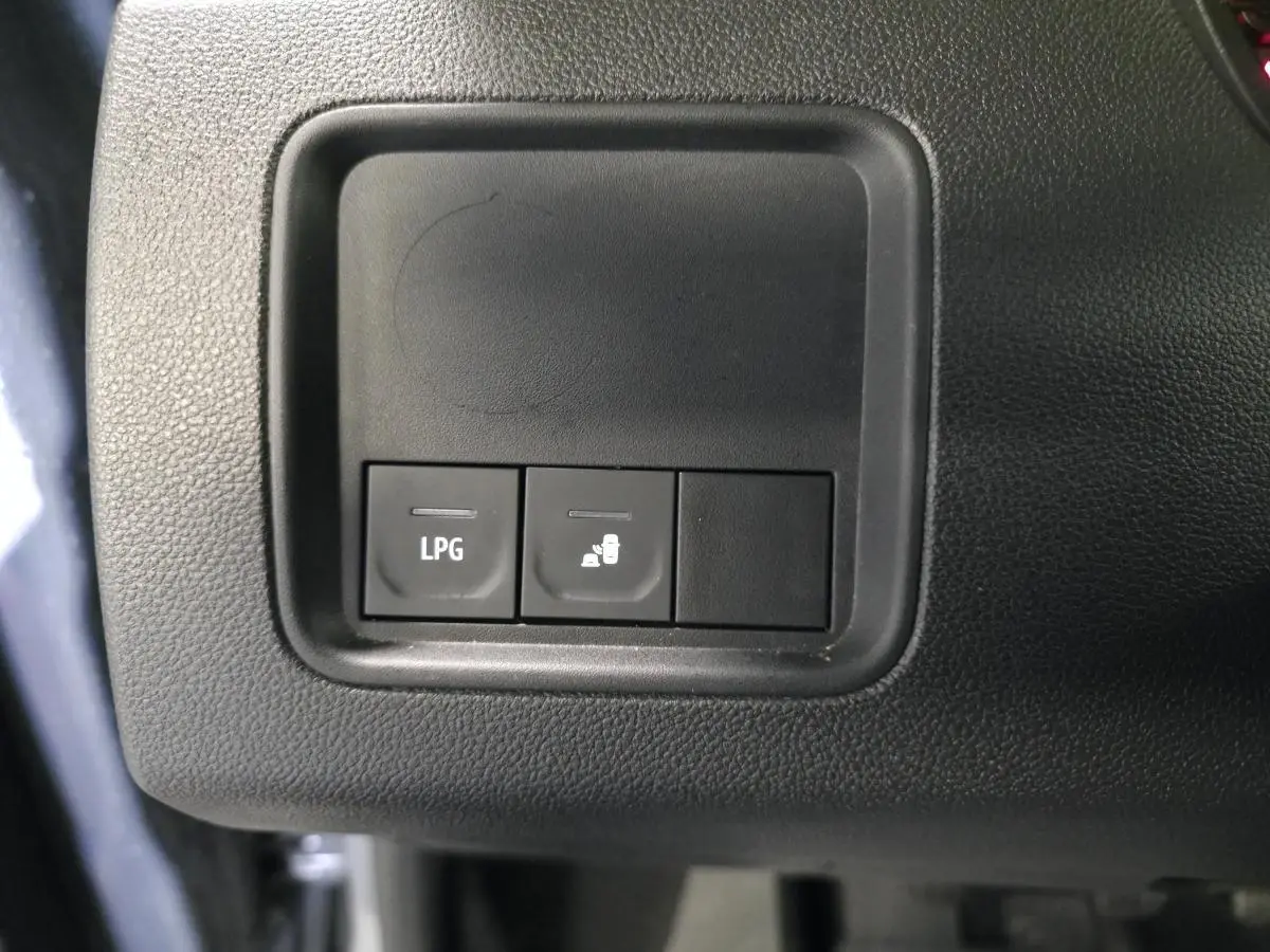 Gros plan sur les boutons de commande LPG et verrouillage de la trappe à carburant du Dacia Duster gris.