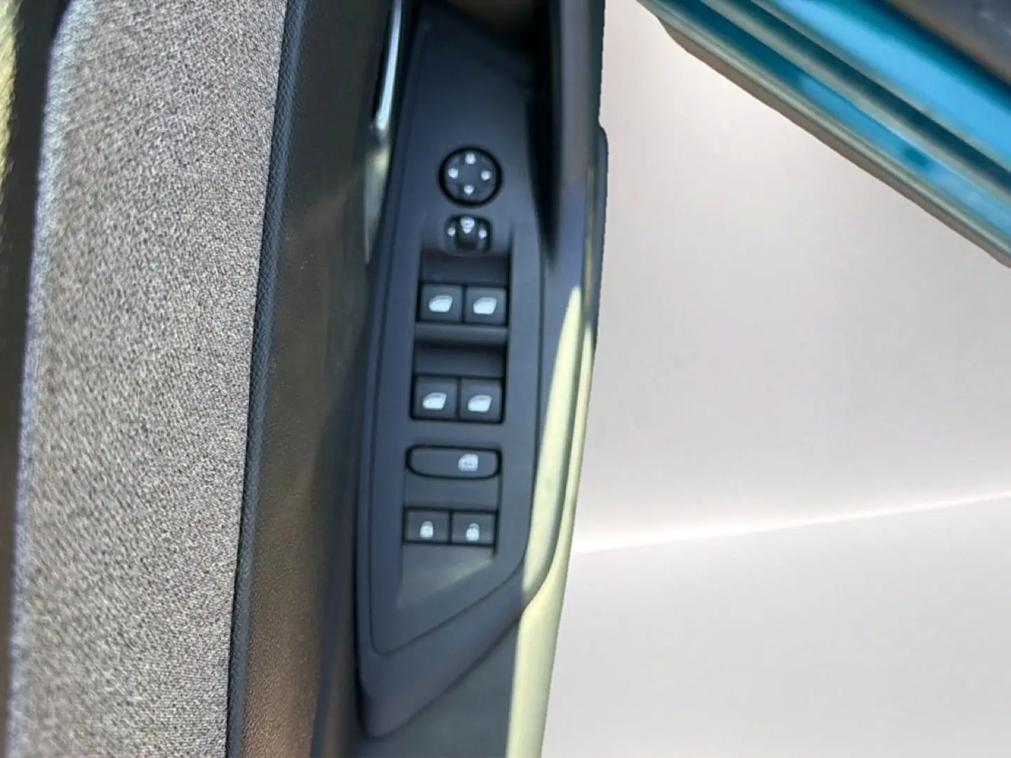 Gros plan sur la commande des vitres électriques côté gauche de la porte d'une Peugeot 408 Hybrid 145 allure bleu 2025.