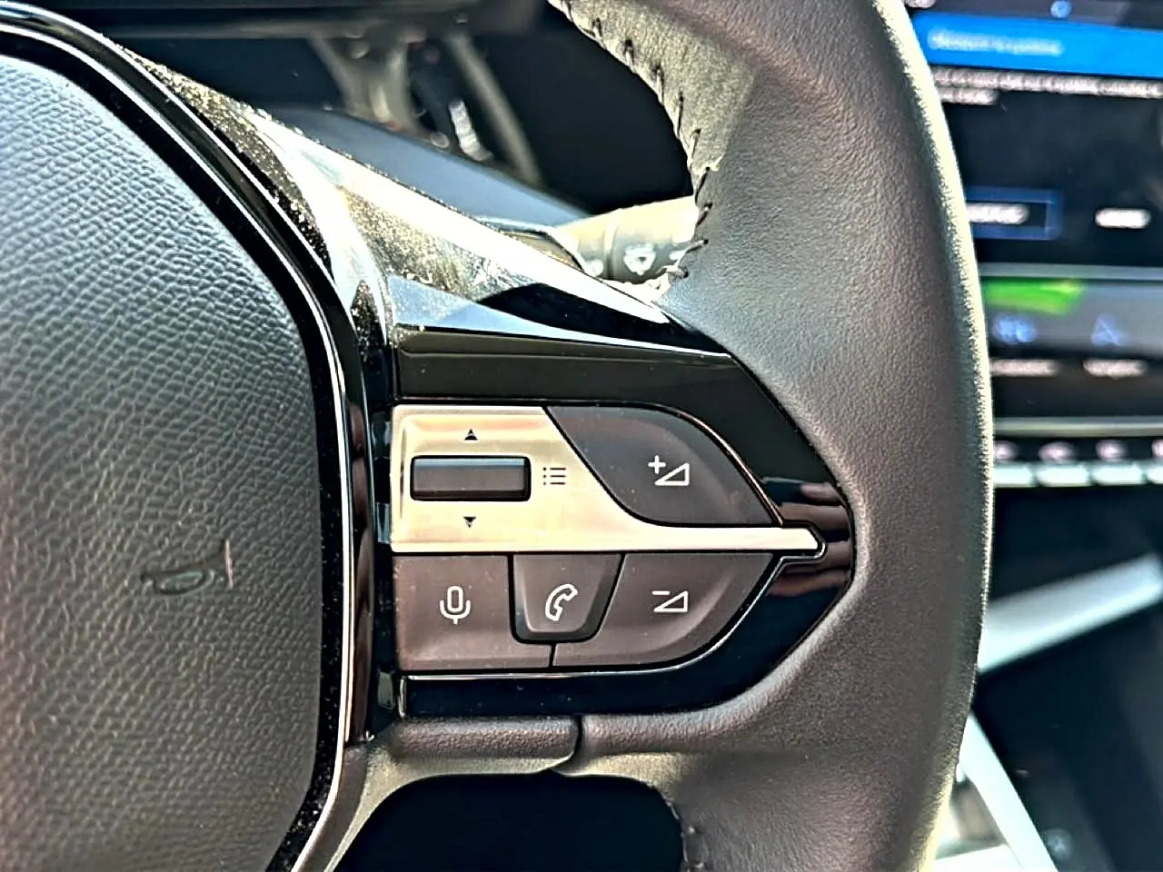 Gros plan sur les commandes vocales et téléphone au volant cuir noir de la Peugeot 408 Hybrid 145 allure 2025.