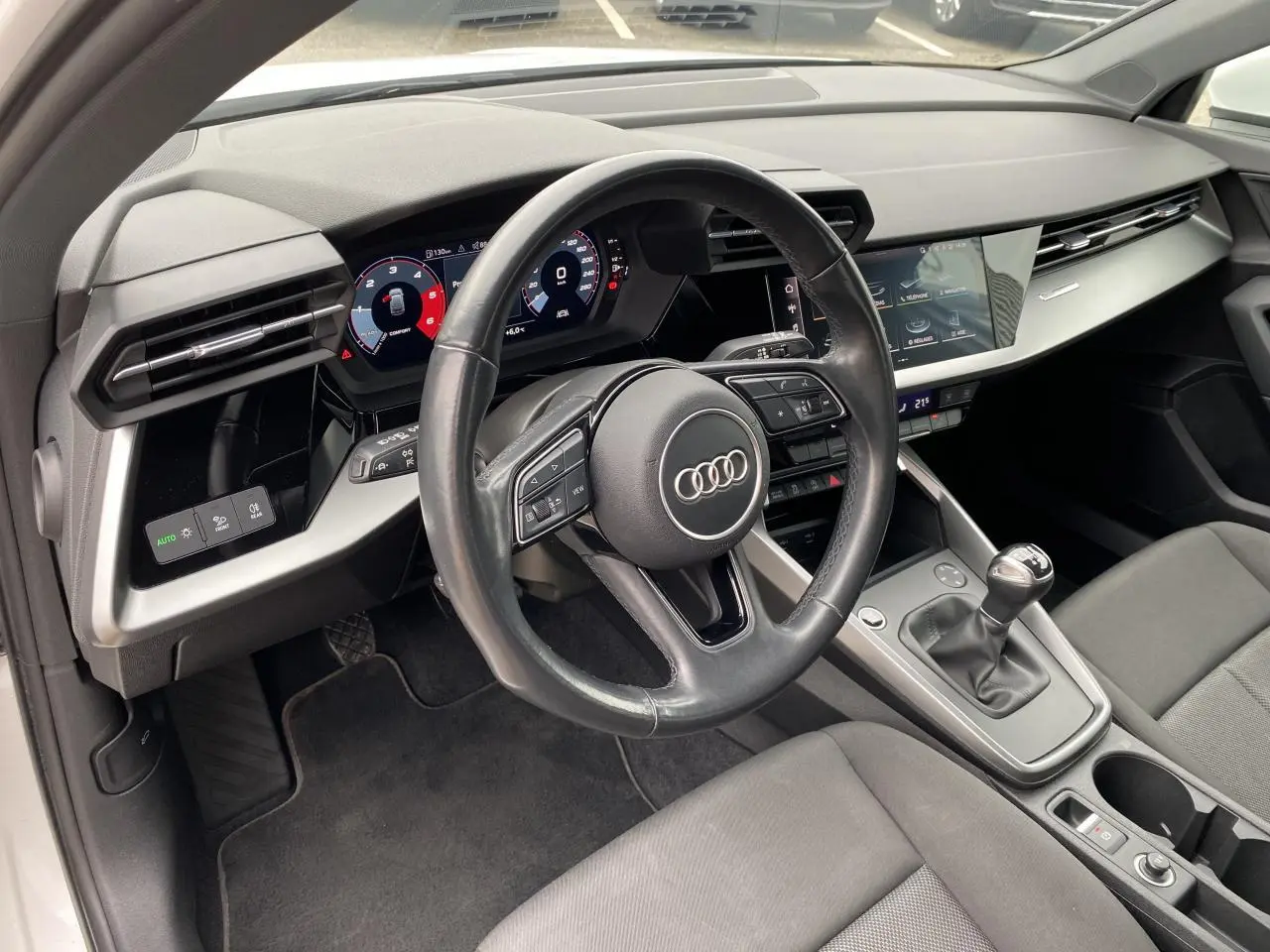 Intérieur de l'Audi A3 Sportback 2022 vu côté conducteur, volant cuir noir et tableau de bord digital.