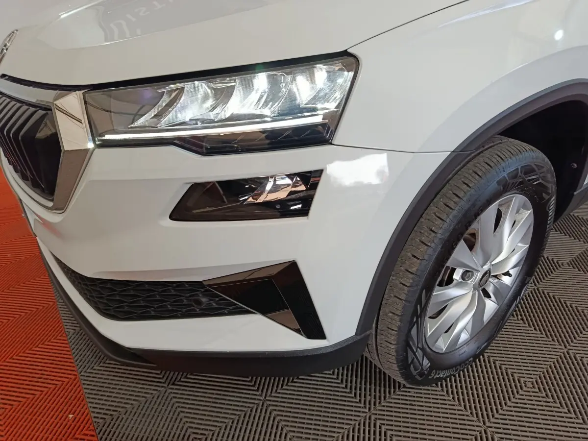 Gros plan sur l’avant droit du Skoda Karoq blanc, mettant en valeur le phare LED et la roue avec jante argentée.