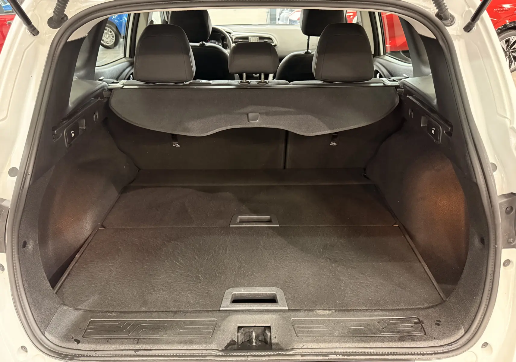 Coffre ouvert vu de l’arrière d’un Renault Kadjar blanc Glacier, montrant l’espace de chargement et la plage arrière noire.