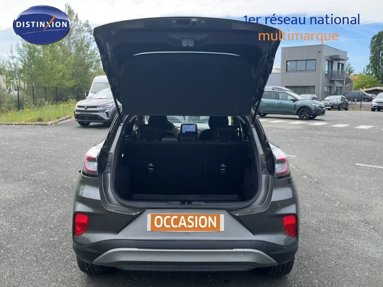 Vue arrière d’un Ford Puma gris 2021 avec coffre ouvert, mettant en valeur l’espace de chargement et les feux arrière.