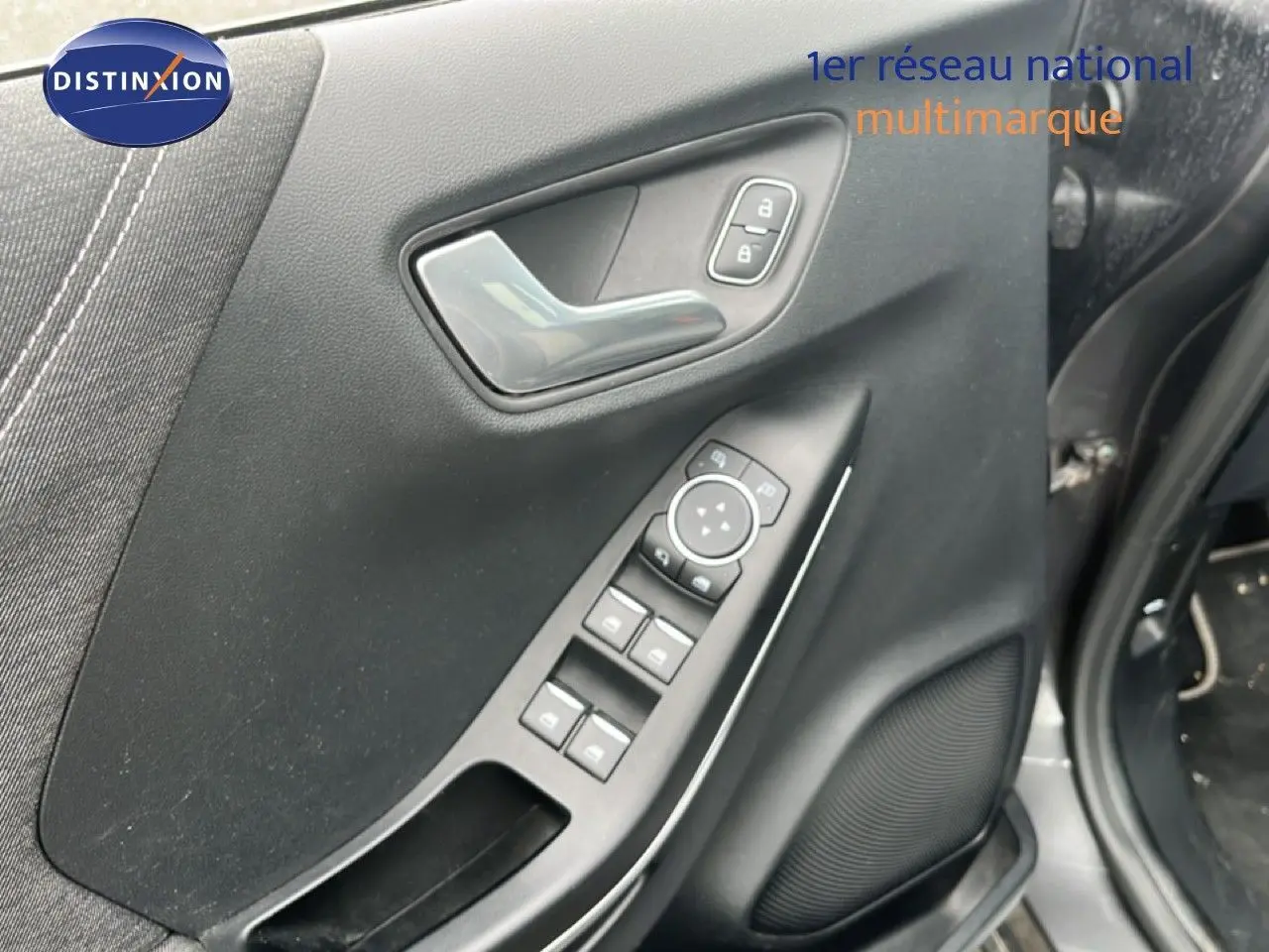 Gros plan sur la porte avant gauche du Ford Puma gris 2021, montrant les commandes électriques et la poignée intérieure.