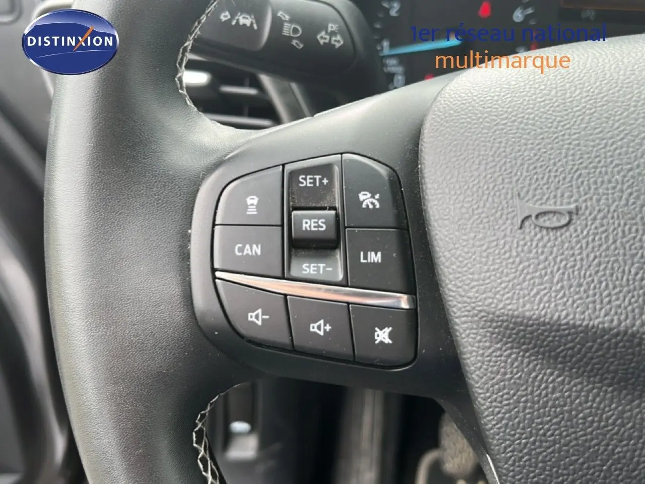 Gros plan sur les commandes au volant du Ford Puma gris 2021, mettant en valeur les boutons de régulateur et volume.