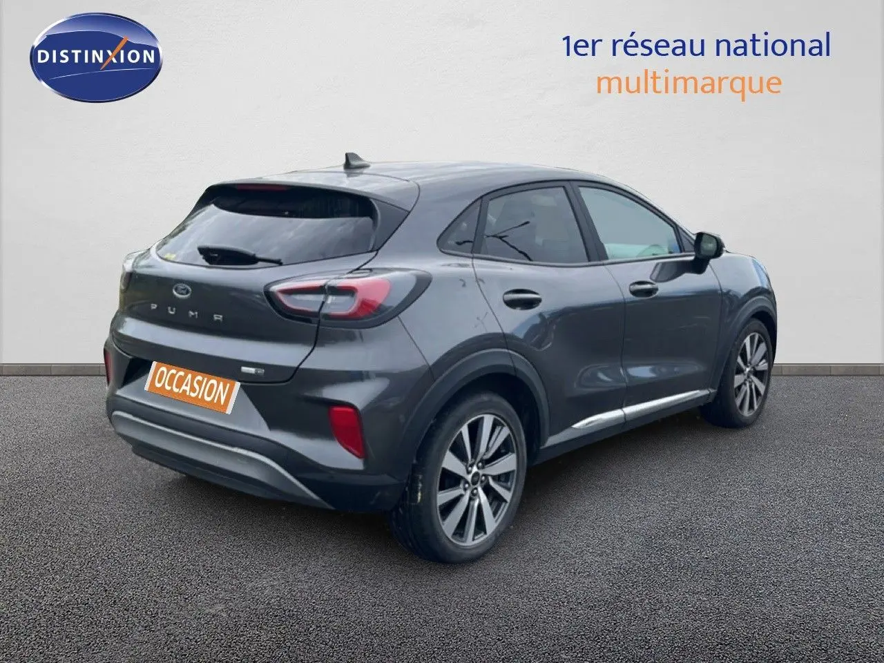 Ford Puma gris vue 3/4 arrière droit, SUV compact avec feux arrière distinctifs et jantes alliage.