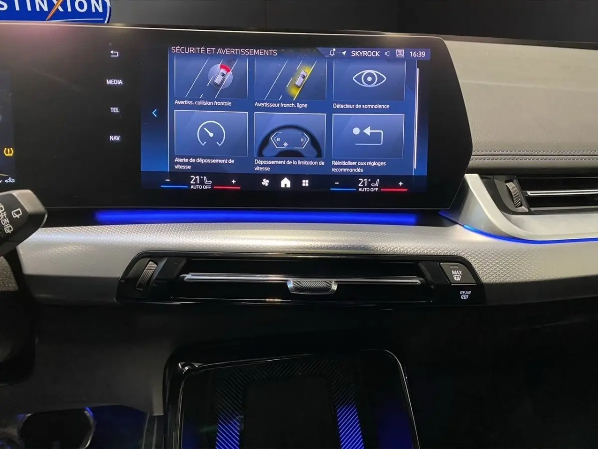 Vue rapprochée du tableau de bord et écran tactile central du BMW X1 noir 2025 avec éclairage d'ambiance bleu.