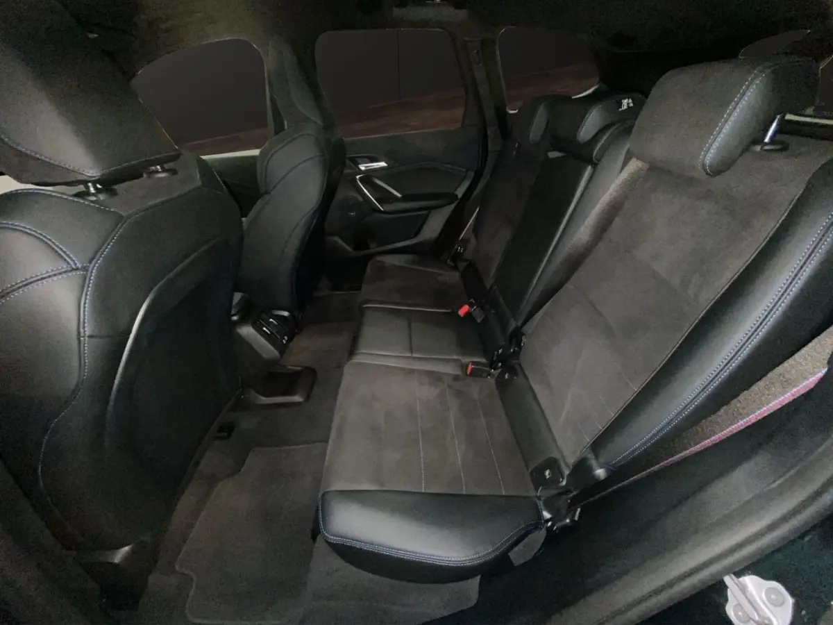 Vue intérieure arrière côté droit du BMW X1 2025 noir, sièges en cuir et alcantara avec surpiqûres bleues.
