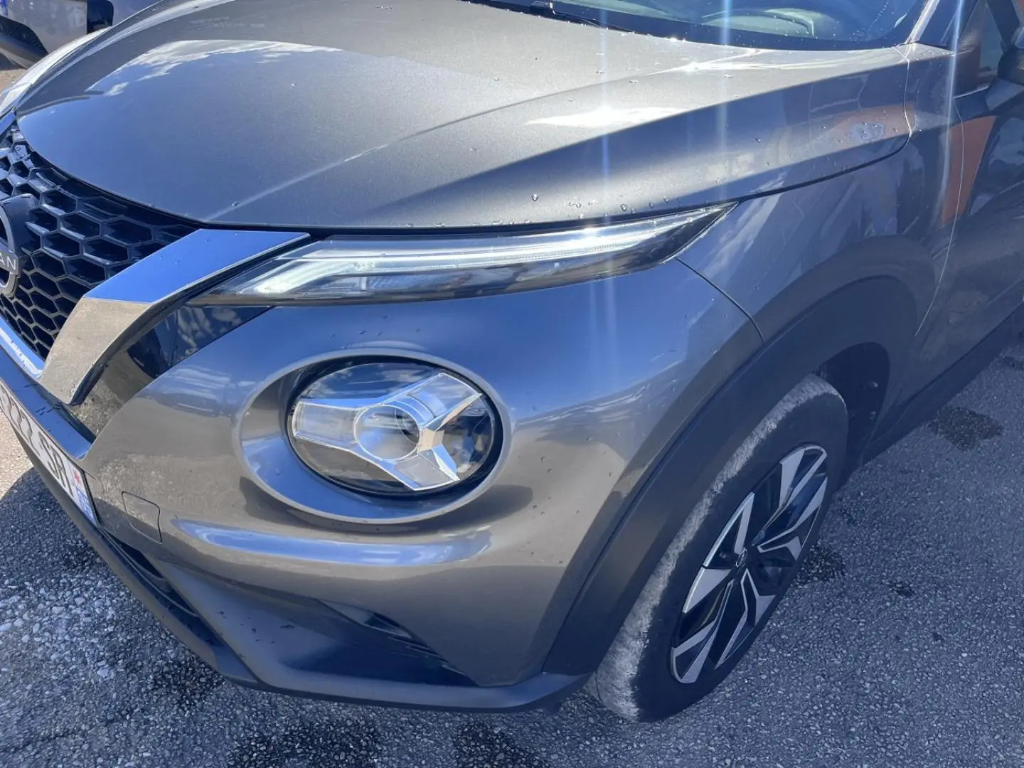 Vue 3/4 avant droit du Nissan Juke 2023 gris Argile Spéciale avec phares LED et jantes bi-ton.