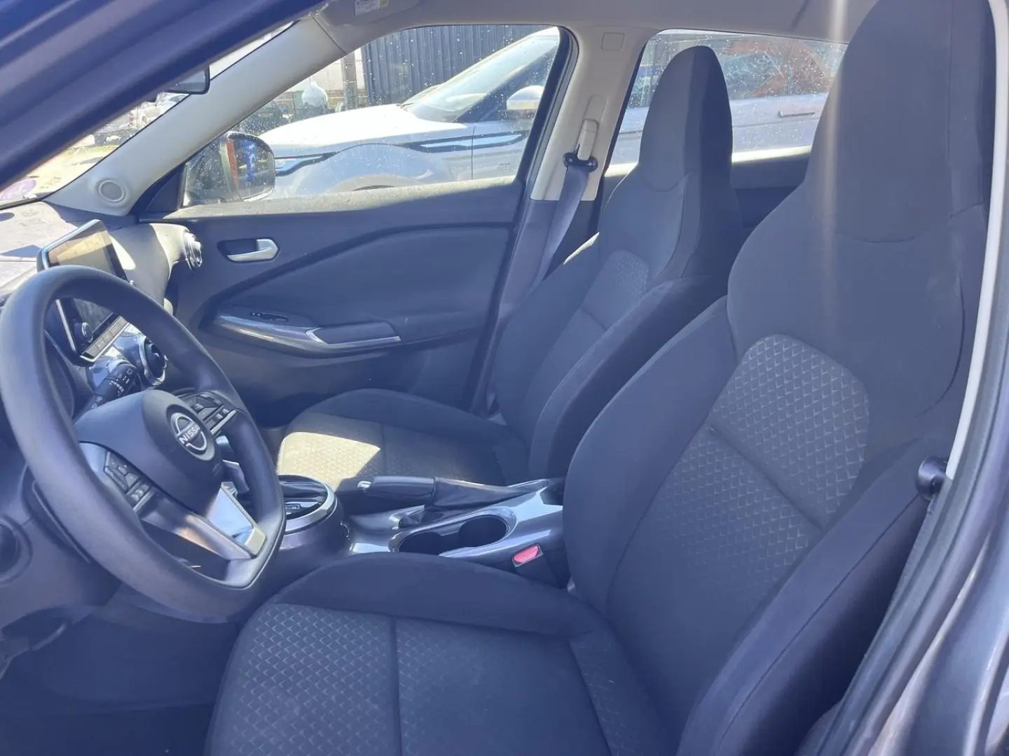 Intérieur avant du Nissan Juke 2023, vue côté conducteur, sièges tissu noir et volant multifonction.