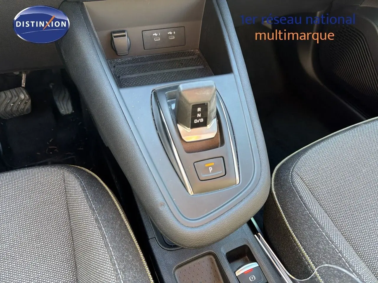 Gros plan sur la console centrale et levier de vitesse automatique du Renault Symbioz gris, avec sièges tissu gris foncé.