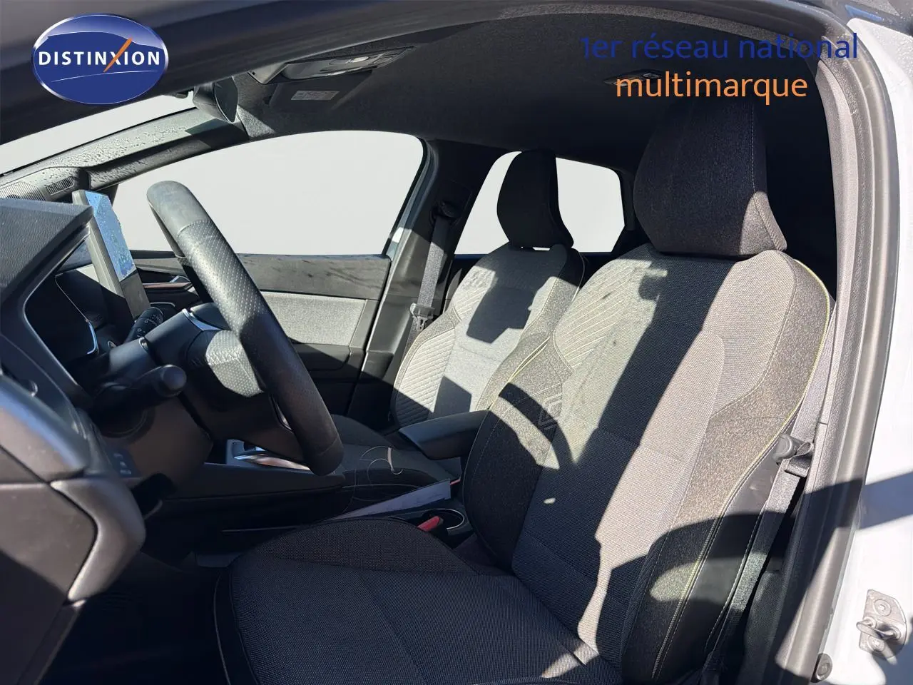Vue intérieure côté conducteur de la Renault Symbioz 2025, sièges tissu gris clair avec surpiqûres jaunes.