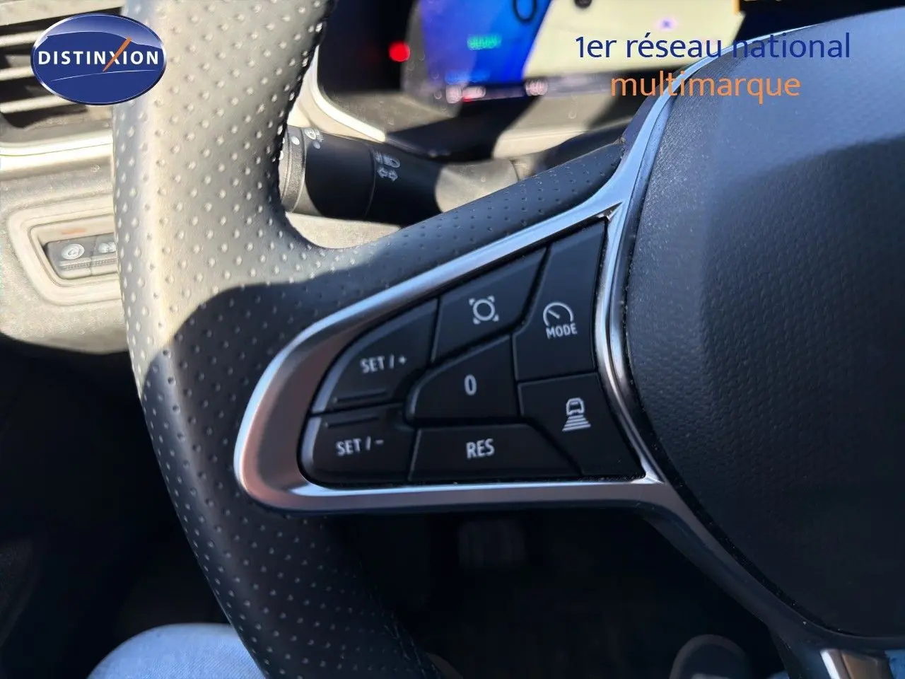 Gros plan sur les commandes au volant perforé du Renault Symbioz gris Rafale, mettant en valeur les boutons de régulateur et mode de conduite.