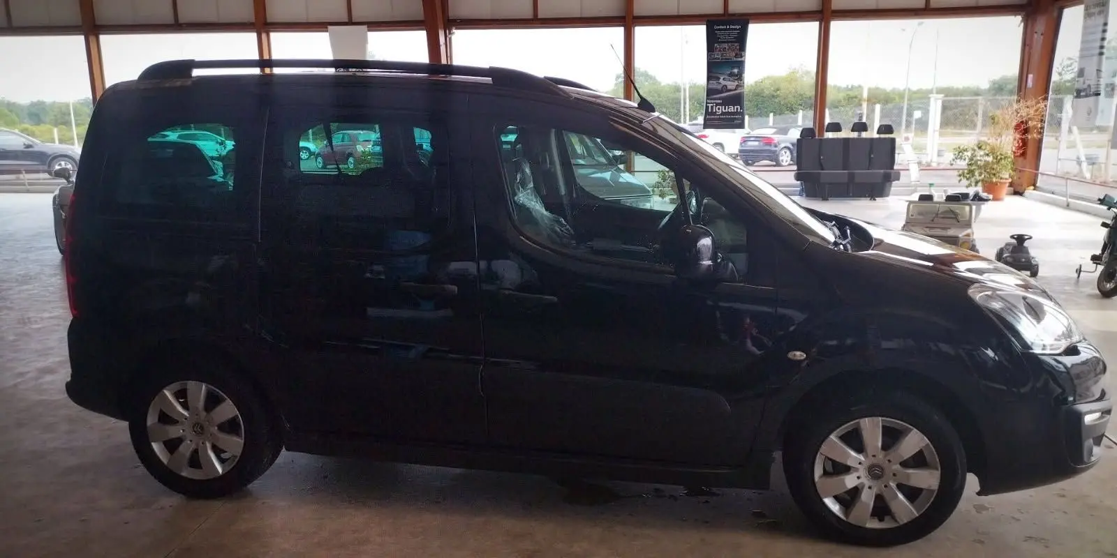Profil côté gauche d'un Citroën Berlingo noir 2016 diesel, 5 places, avec jantes alliage et barres de toit visibles.