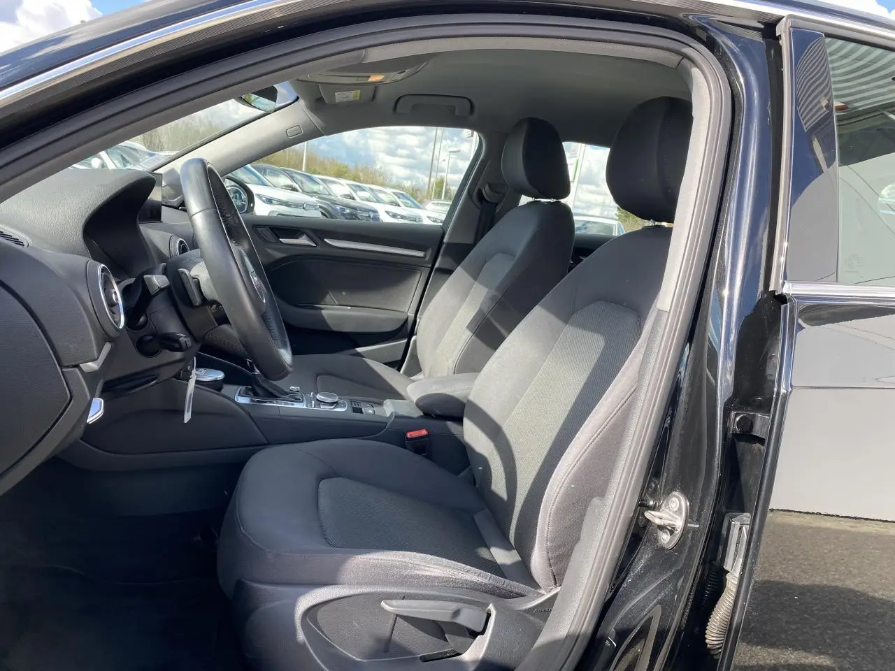 Vue intérieure côté conducteur de l'Audi A3 Sportback 2020 noir mythic metal, sièges tissu gris et console centrale visible.