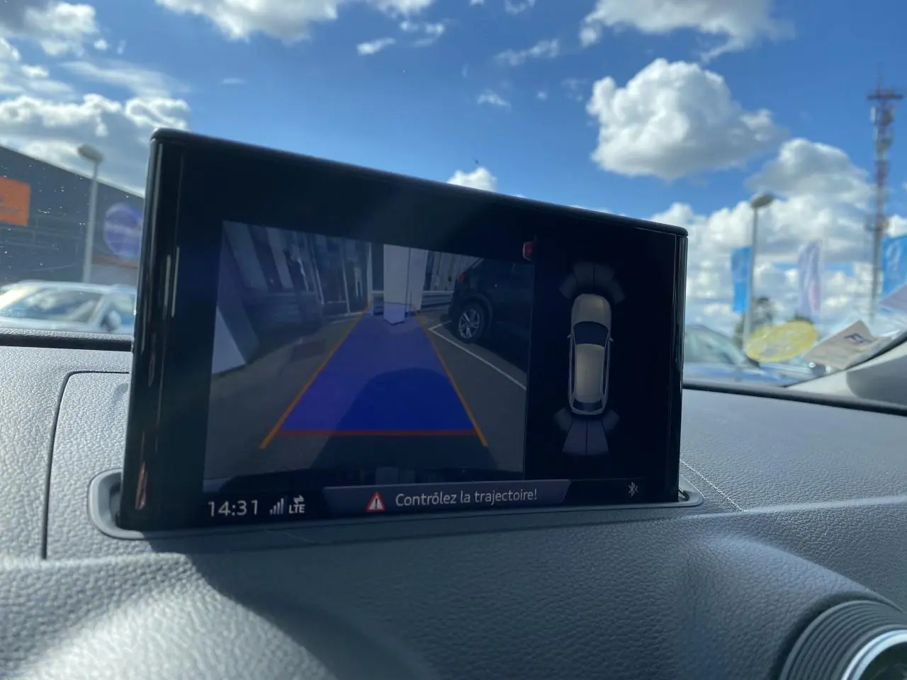 Écran central de l'Audi A3 Sportback 2020 montrant la caméra de recul et l'aide au stationnement en extérieur lumineux.