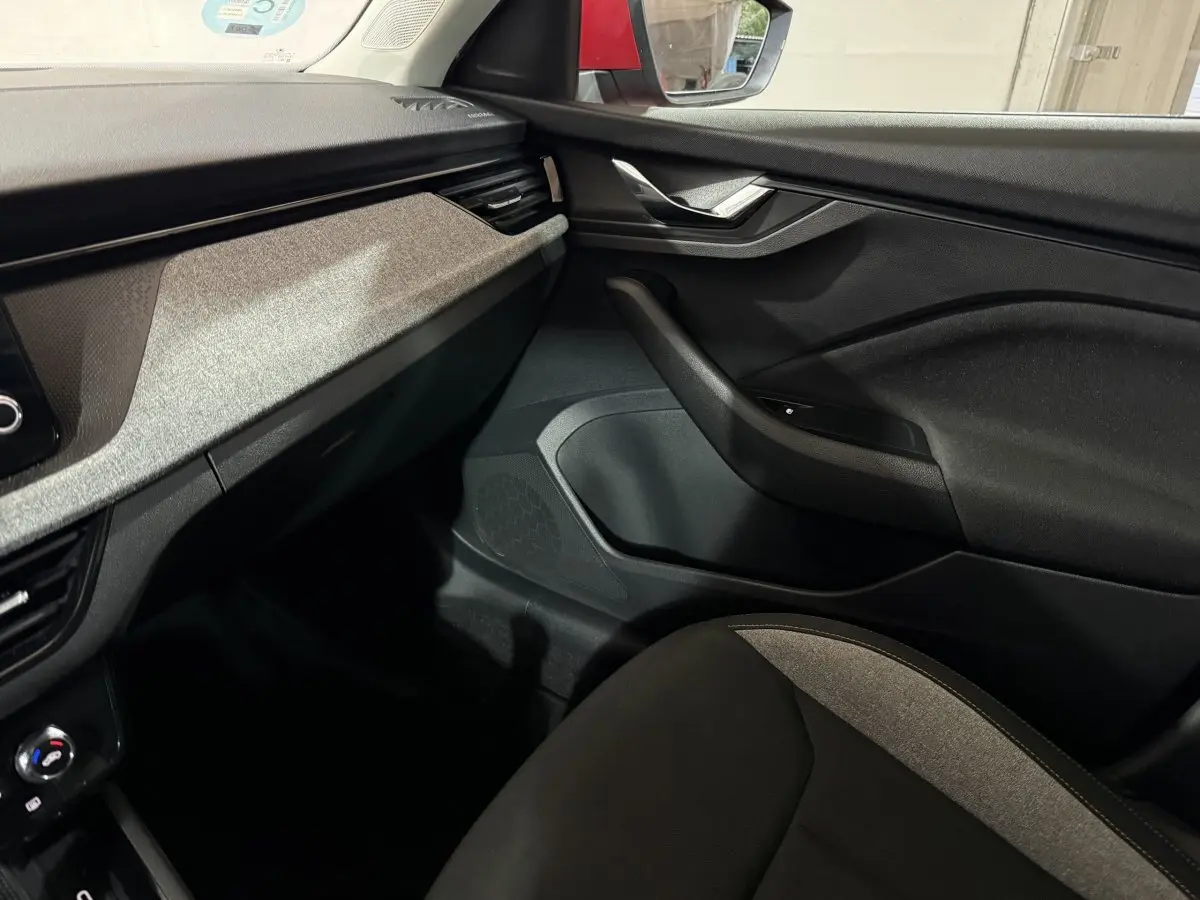 Vue intérieure côté passager du tableau de bord et porte noire avec insert gris du Skoda Kamiq 2024.