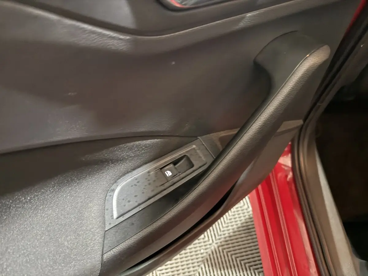 Détail de la porte intérieure côté conducteur d’un Skoda Kamiq rouge avec bouton de verrouillage des vitres.