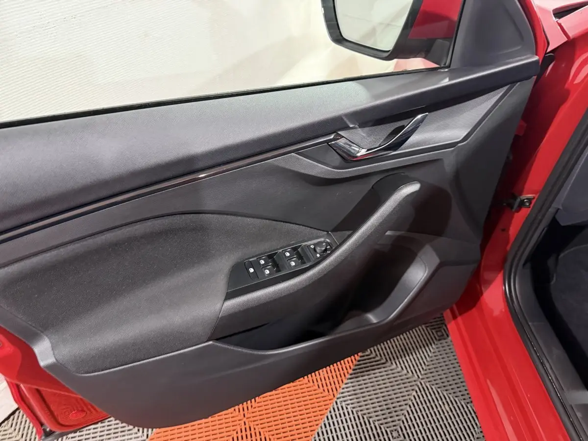 Vue intérieure de la porte avant gauche rouge du Skoda Kamiq 2024 avec commandes électriques et poignée noire.