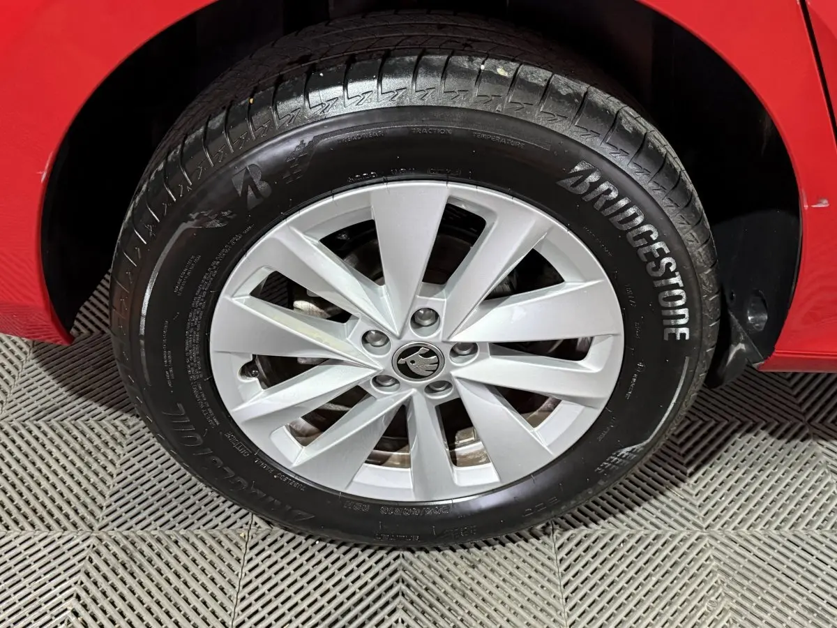 Gros plan sur la roue avant gauche d’une Skoda Kamiq rouge avec jante argentée et pneu Bridgestone.