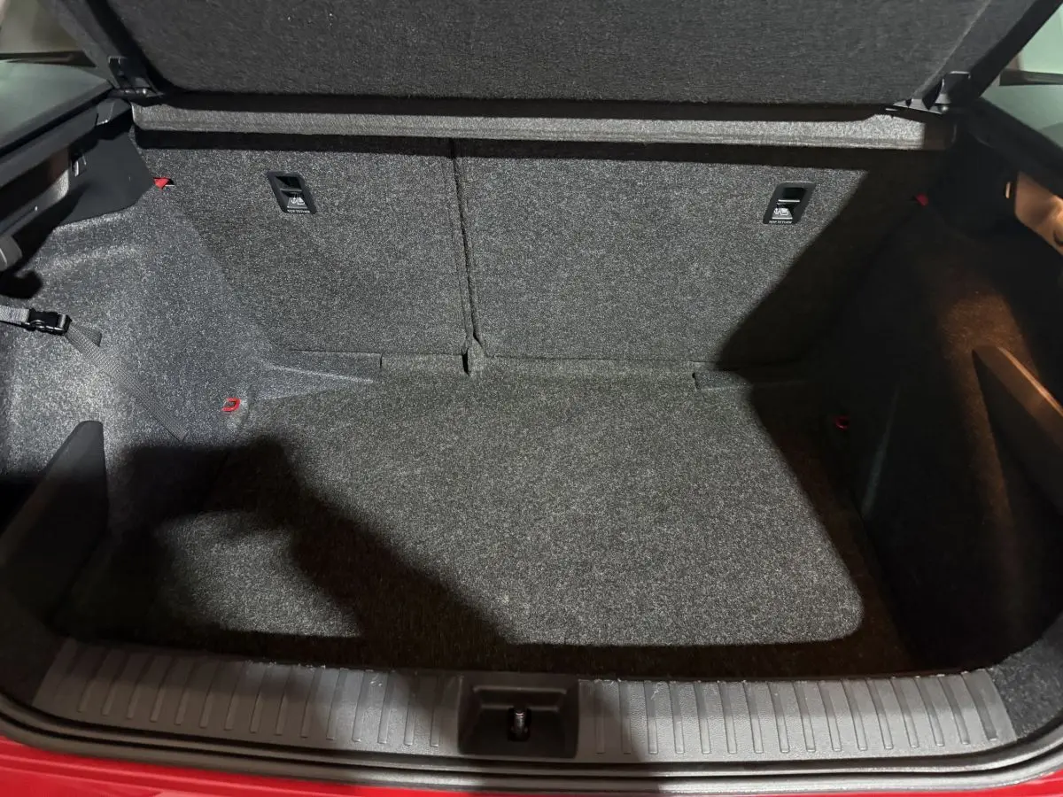 Coffre ouvert vu de face du Skoda Kamiq rouge 2024, montrant l’espace de chargement en moquette grise.