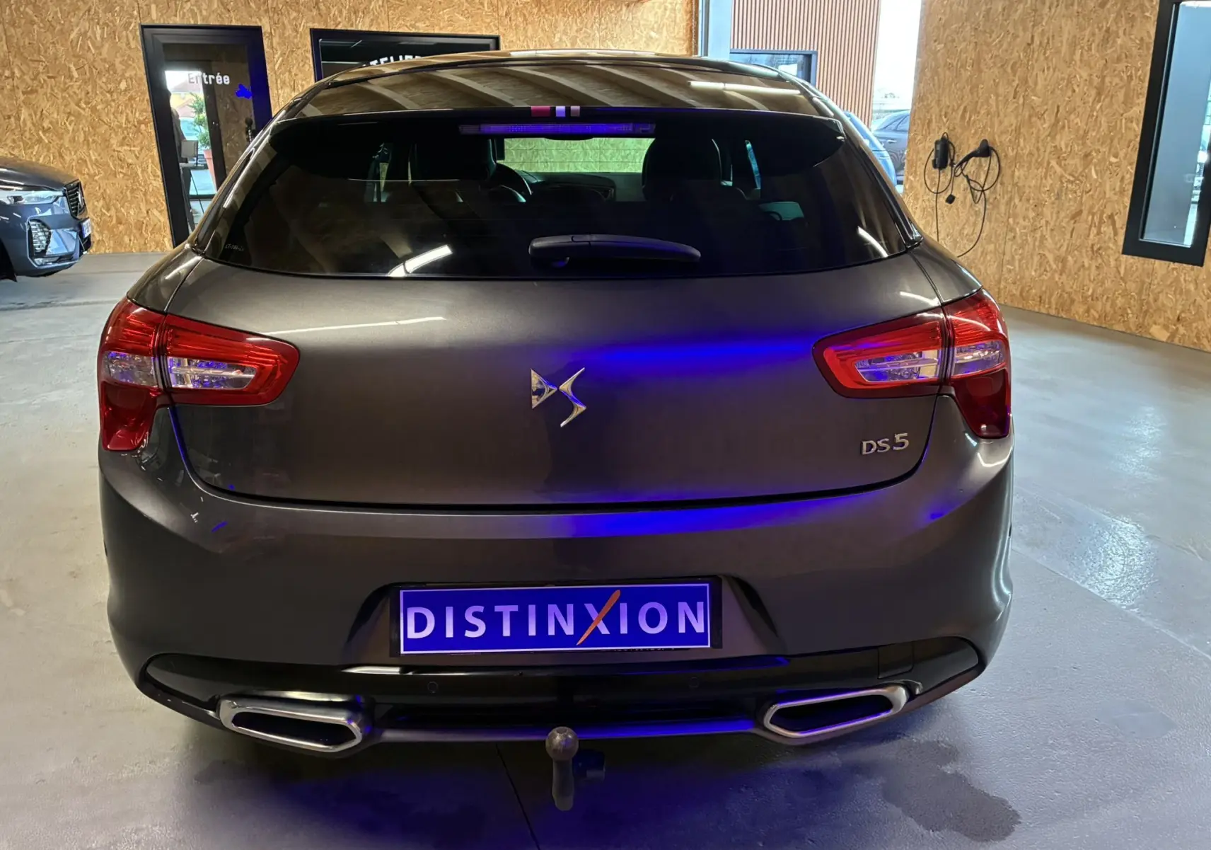 Vue arrière d'une DS5 gris métallisé 2018 avec feux rouges et double sortie d'échappement rectangulaire, en intérieur showroom.