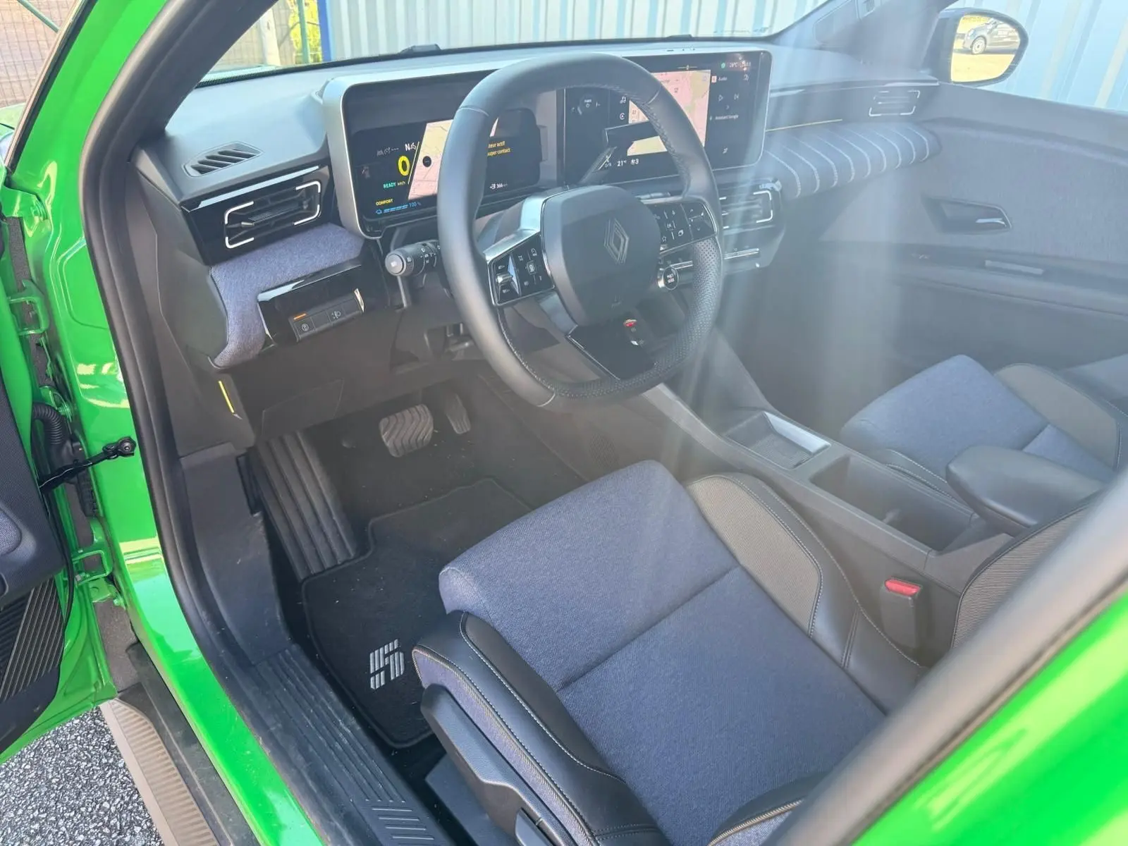 Vue intérieure côté conducteur de la Renault R5 E-TECH 100% électrique Vert Pop, avec sellerie textile bleu et tableau de bord numérique.