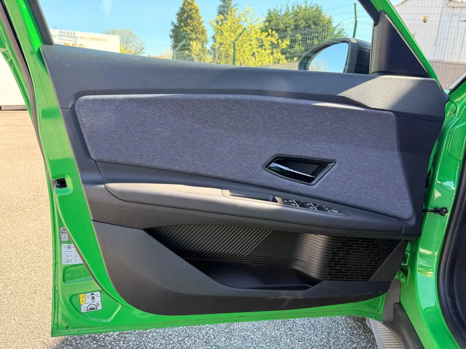 Vue côté gauche de la porte avant verte Renault R5 E-TECH avec habillage textile gris et commandes électriques.