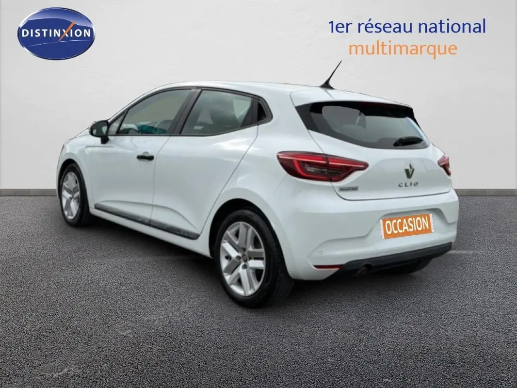 Vue 3/4 arrière droite d'une Renault Clio blanche 2021 avec feux arrière LED et jantes alliage, stationnée sur sol gris.
