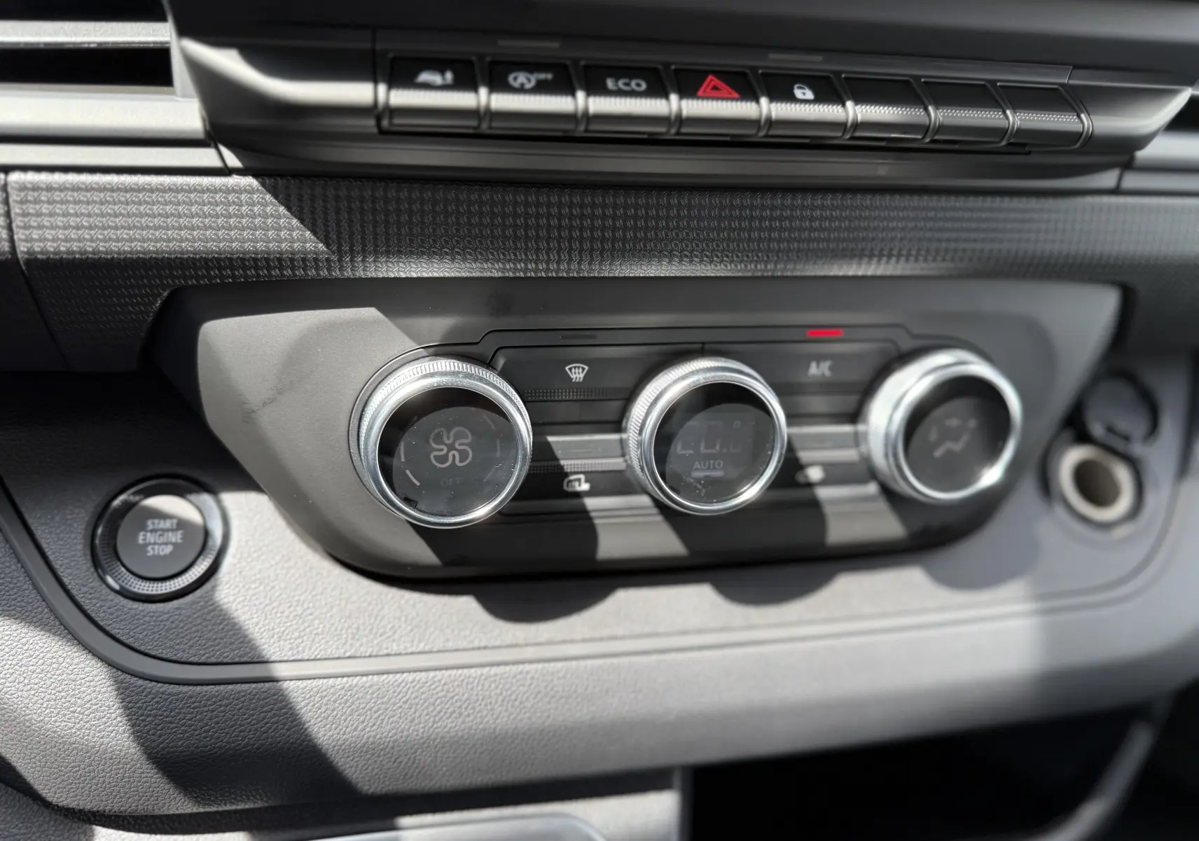 Gros plan sur la console centrale du Renault Trafic Fourgon blanc 2025, montrant les commandes de climatisation et le bouton Start Engine Stop.