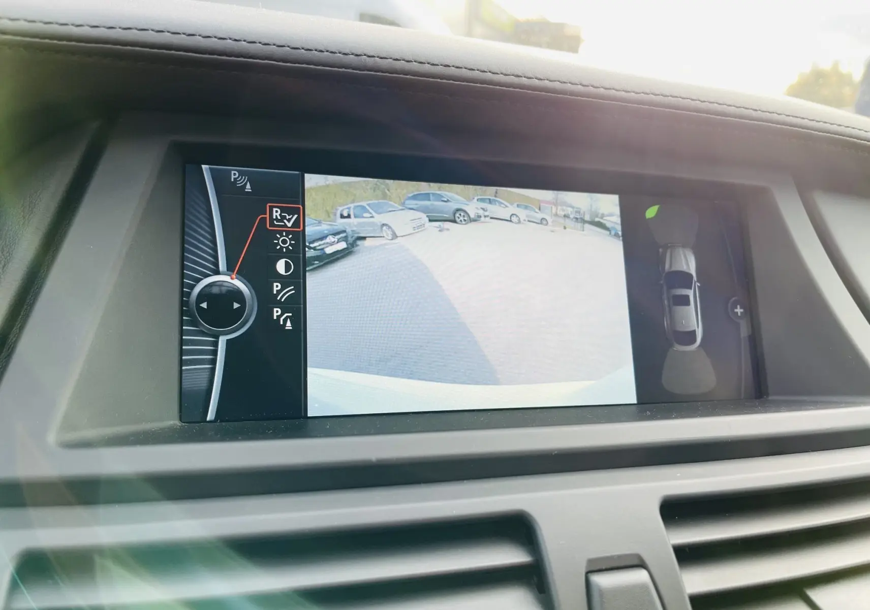 Écran central du BMW X6 blanc montrant la caméra de recul avec vue arrière et top view du véhicule.