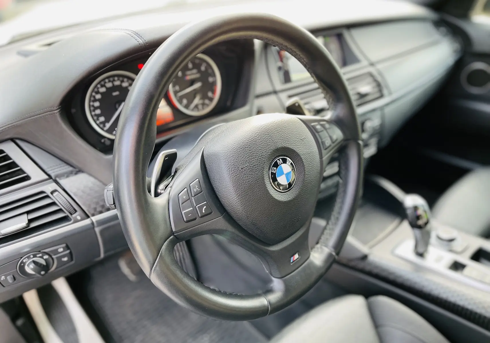 Vue rapprochée du volant M en cuir noir et du tableau de bord du BMW X6 blanc, version 50D M 2013.